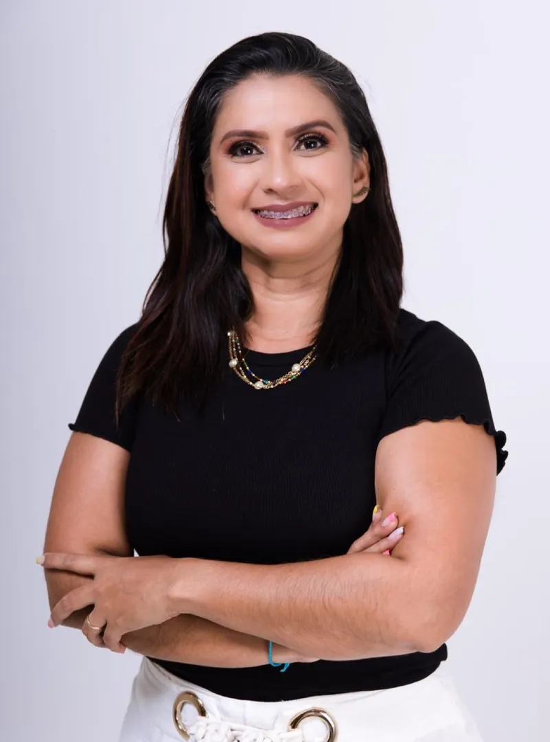 Ellen Aranha, psicóloga, de blusa preta e braços cruzados, sorrindo
